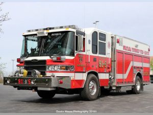 A red and white fire truck with "Suffield Township Fire Department" and "911" on its side, parked on a paved surface. The truck has multiple compartments and emergency lights on top.
