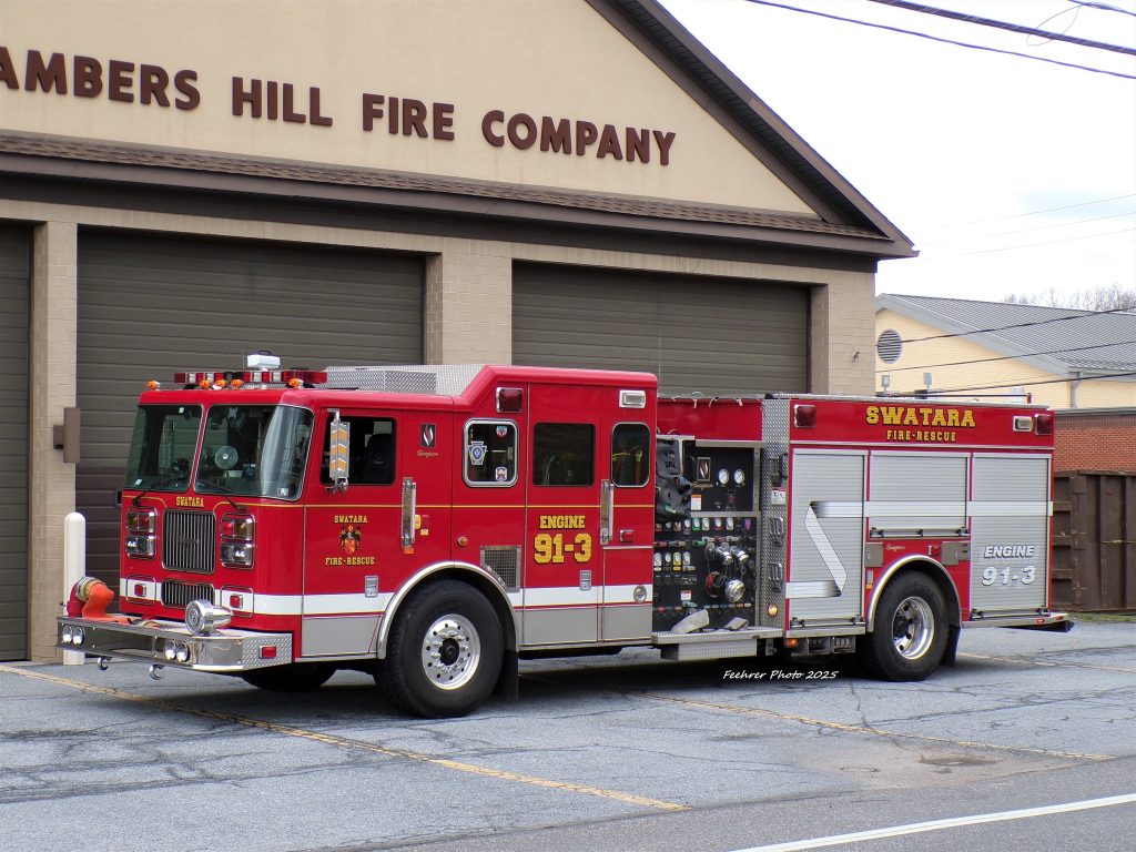 A bright red and white fire engine, labeled "Swatara Fire-Rescue," is parked in front of a building labeled "Chambers Hill Fire Company." The truck is numbered "91-3" and equipped with hoses and control panels.